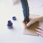 woman's hand addressing an envelope with quill pen