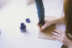 woman's hand addressing an envelope with quill pen