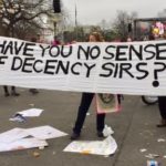 Protesters holding sign that says "Have you no sense of decency sirs?"