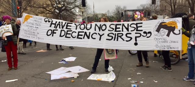 Protesters holding sign that says "Have you no sense of decency sirs?"