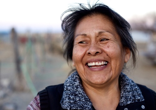 A woman in midlife smiling while standing out of doors.