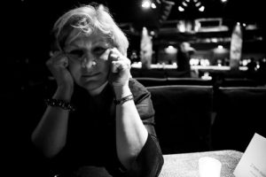 Black and white photo of older woman with grey hair with a sad expression