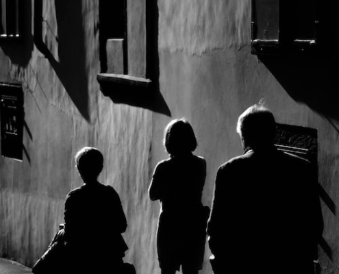 A family dealing with parental estrangement walking on a dark path alongside a building