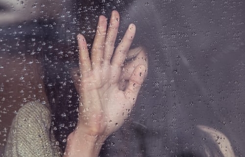 Woman's hand on a window thinking about why divorce hurts