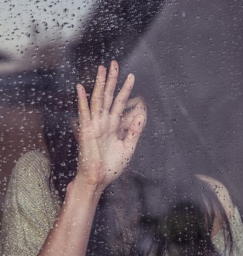 Woman's hand on a window thinking about why divorce hurts