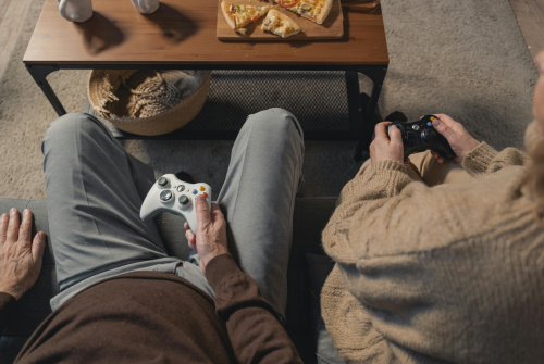 Couple sitting together playing video games, symbolizing routine and comfort in a long term relationship
