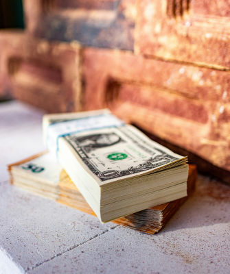 Hiding assets in divorce by MarHidden Assets- Is There a Penalty for Hiding Them in Divorce Hidden Assets- Is There a Penalty for Hiding Them in Divorce by Marek Studzinski on Unsplash Stack of U.S. dollar bills placed on a ledge beside a brick wall, symbolizing hidden or undisclosed financial assets in the context of divorce.