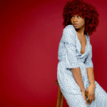 Woman seated against a red background, looking away thoughtfully, representing emotional reflection and financial impact during divorce.