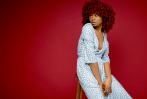 Woman seated against a red background, looking away thoughtfully, representing emotional reflection and financial impact during divorce.
