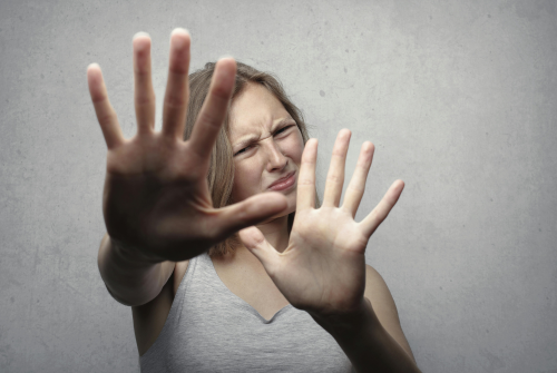 Woman holding up her hands in resistance, showing discomfort and emotional reaction to difficult news