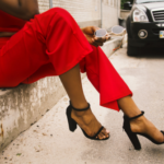 Woman in a red outfit sitting outdoors holding sunglasses, representing confidence and dating after divorce