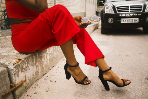 Woman in a red outfit sitting outdoors holding sunglasses, representing confidence and dating after divorce