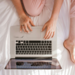 Woman using a laptop while sitting on a bed, researching how to file for divorce and prepare for the next steps