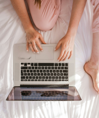 Woman using a laptop while sitting on a bed, researching how to file for divorce and prepare for the next steps