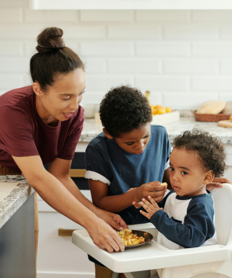 Mother feeding her children in a kitchen, representing stability and care in a parallel parenting environment
