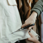 Hands cutting fabric with scissors, symbolizing budgeting, financial adjustments, and managing living expenses after divorce.