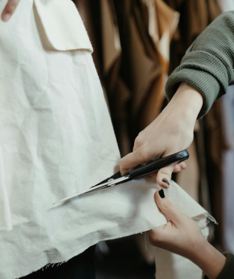Hands cutting fabric with scissors, symbolizing budgeting, financial adjustments, and managing living expenses after divorce.