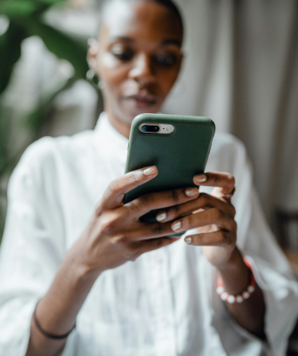 Woman holding a smartphone and reviewing social media content in a quiet indoor setting.