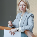 Professional woman holding documents and glasses, representing a divorce attorney helping women navigate divorce decisions