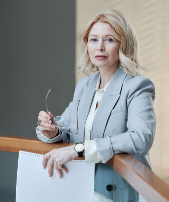 Professional woman holding documents and glasses, representing a divorce attorney helping women navigate divorce decisions
