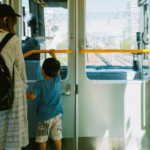 Mother and young child standing together inside a train, looking out through the front window during their journey.