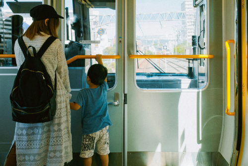 Mother and young child standing together inside a train, looking out through the front window during their journey.