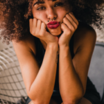 Curly lady sitting and pouting her lips