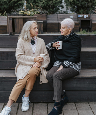 Two older women sitting together outdoors, representing a committed couple considering a civil union