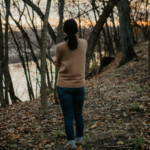 Woman walking alone through the woods, reflecting on whether she should get a divorce