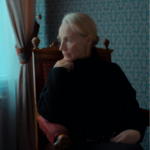 Woman sitting alone by a window, looking thoughtful, symbolizing emotional distance in a silent divorce