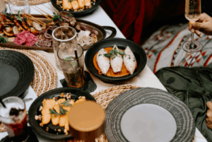 A celebratory dinner table with cocktails, champagne, and shared dishes, symbolizing women celebrating freedom and new beginnings after divorce.