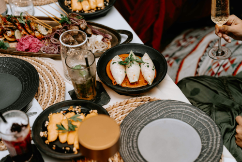 A celebratory dinner table with cocktails, champagne, and shared dishes, symbolizing women celebrating freedom and new beginnings after divorce.
