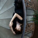 Woman lying on a staircase, appearing emotionally overwhelmed, representing the stress of an unhappy marriage