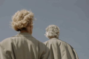 Back of a gray-haired man and woman in raincoats.
